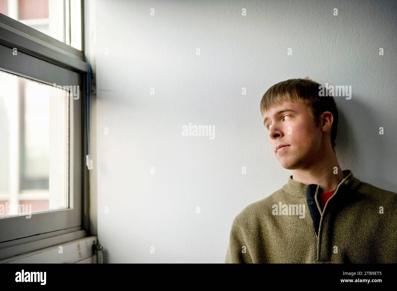 Young man looks out a window of a classroom; Fairbanks, Alaska, United States of America Stock Photo