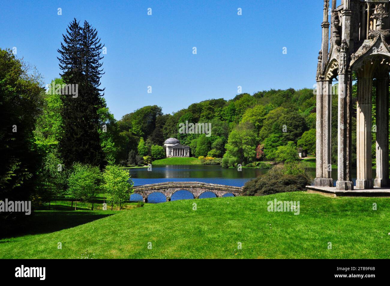 View from beside the Bristol Cross showing the Palladian bridge and across the lake to Pantheon at the Stourhead gardens in Wiltshire.Bright summers d Stock Photo