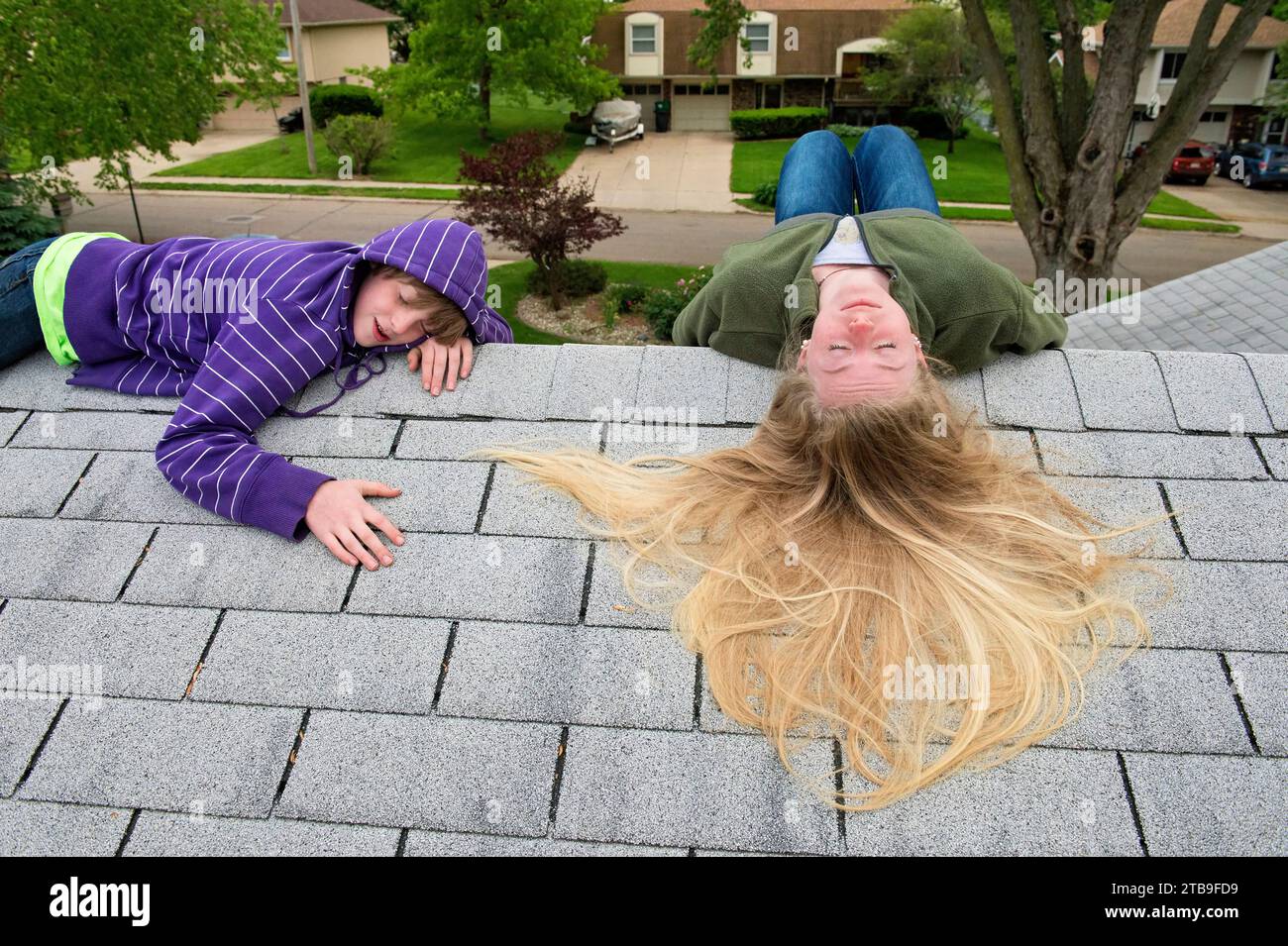 Boy and teenage girl lay on rooftop of house; Elkhorn, Nebraska, United States of America Stock Photo