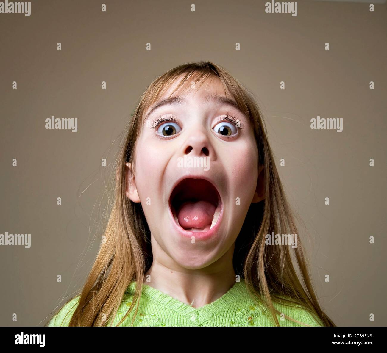 Young girl opening her mouth wide and shows the camera an excited expression; Studio Stock Photo