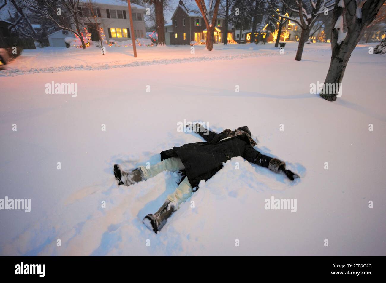 Girl makes snow angels in the pristine snow; Lincoln, Nebraska, United States of America Stock Photo