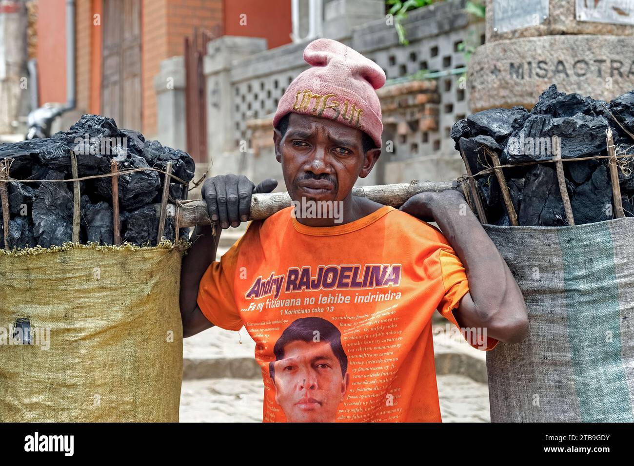 Malagasy man carrying big bags of charcoal on his shoulders in the city Fianarantsoa, Haute Matsiatra Region, Central Highlands, Madagascar, Africa Stock Photo