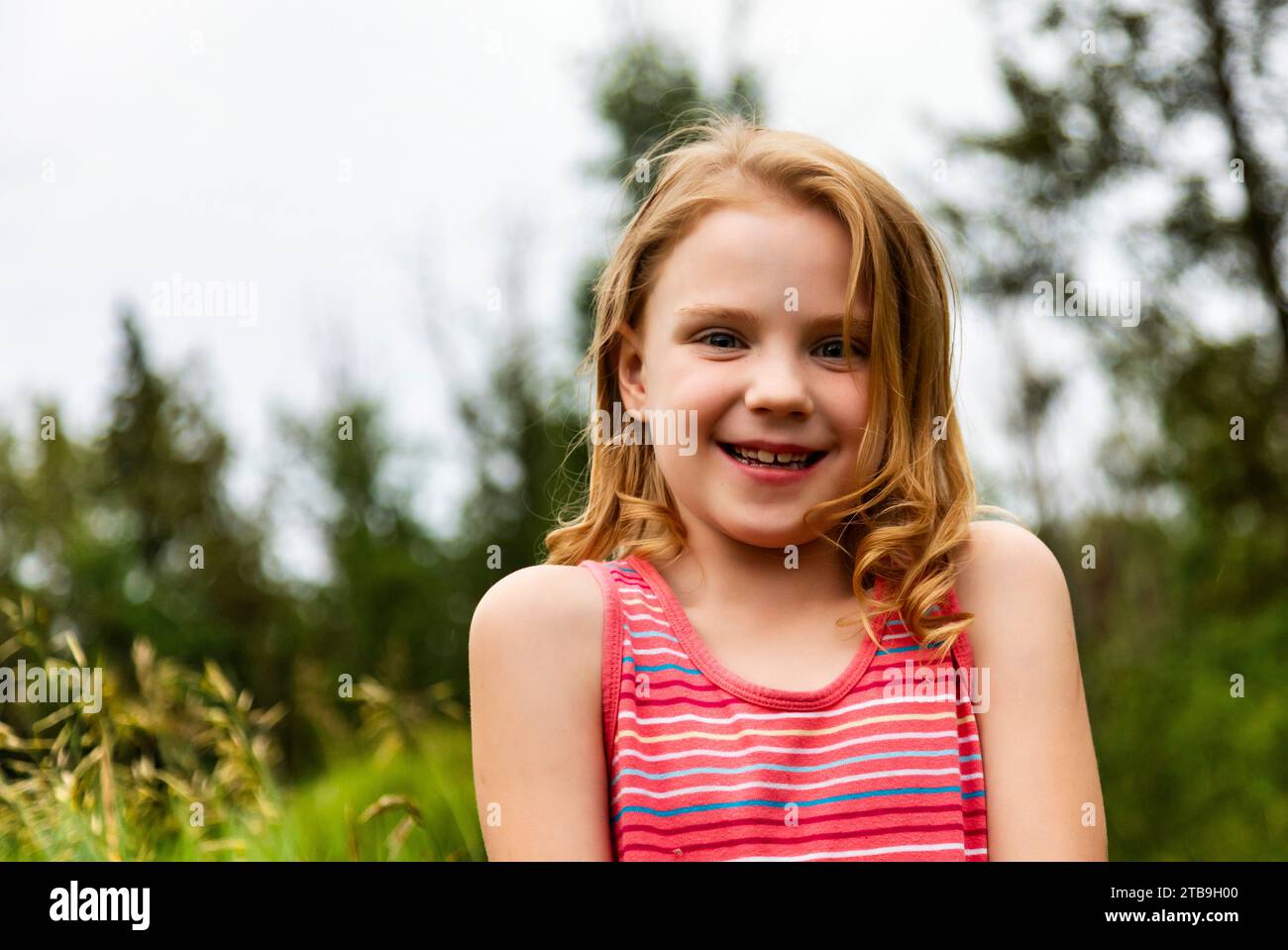 Portrait of a young girl in a park, smiling at the camera; Edmonton, Alberta, Canada Stock Photo