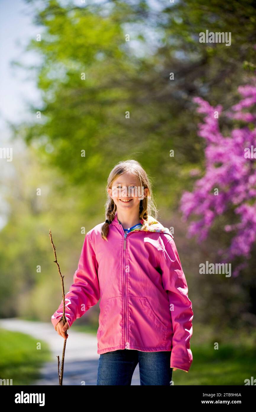 Portrait of a girl wearing a bright pink jacket standing on a walking trail; Brownville, Nebraska, United States of America Stock Photo