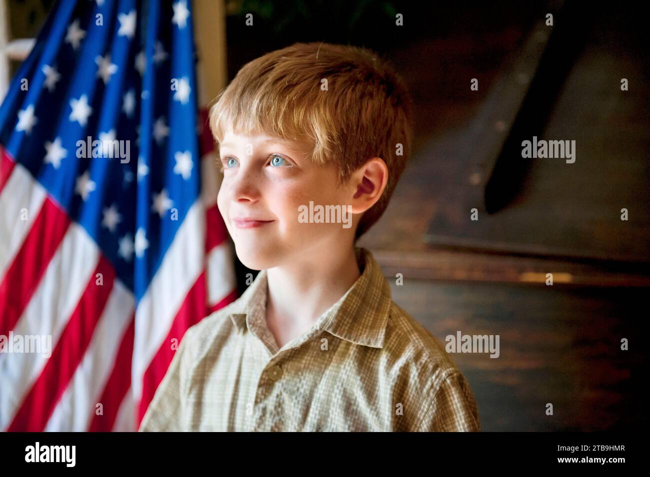 Young, patriotic boy stands before the American flag; Lincoln, Nebraska, United States of America Stock Photo