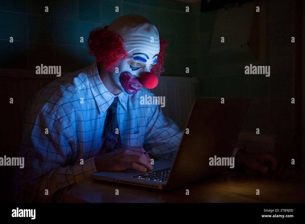 Clown wearing a shirt and tie uses a laptop computer to surf the web; Lincoln, Nebraska, United States of America Stock Photo