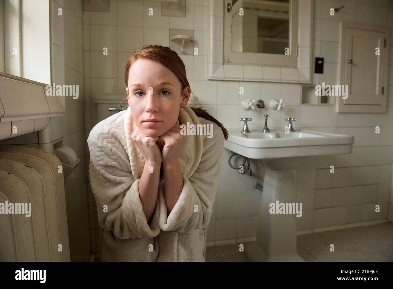 Young woman sits in her bathroom; Lincoln, Nebraska, United States of America Stock Photo