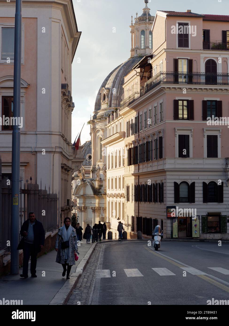 Pedestrians with the dome of the Church of the Most Holy Name of Mary at the Trajan Forum behind. Rome, Lazio Region, Italy, December Stock Photo