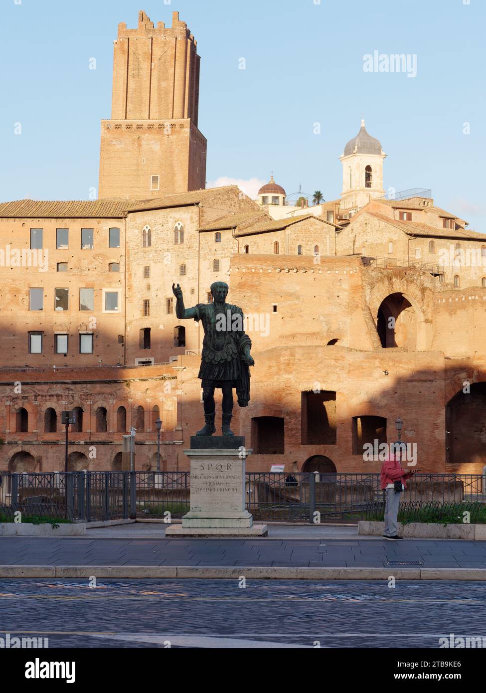 Statue beside a street with historic buildings behind bathed in autumn evening light in the city of Rome, Lazio Region, Italy, December 05, 2023 Stock Photo