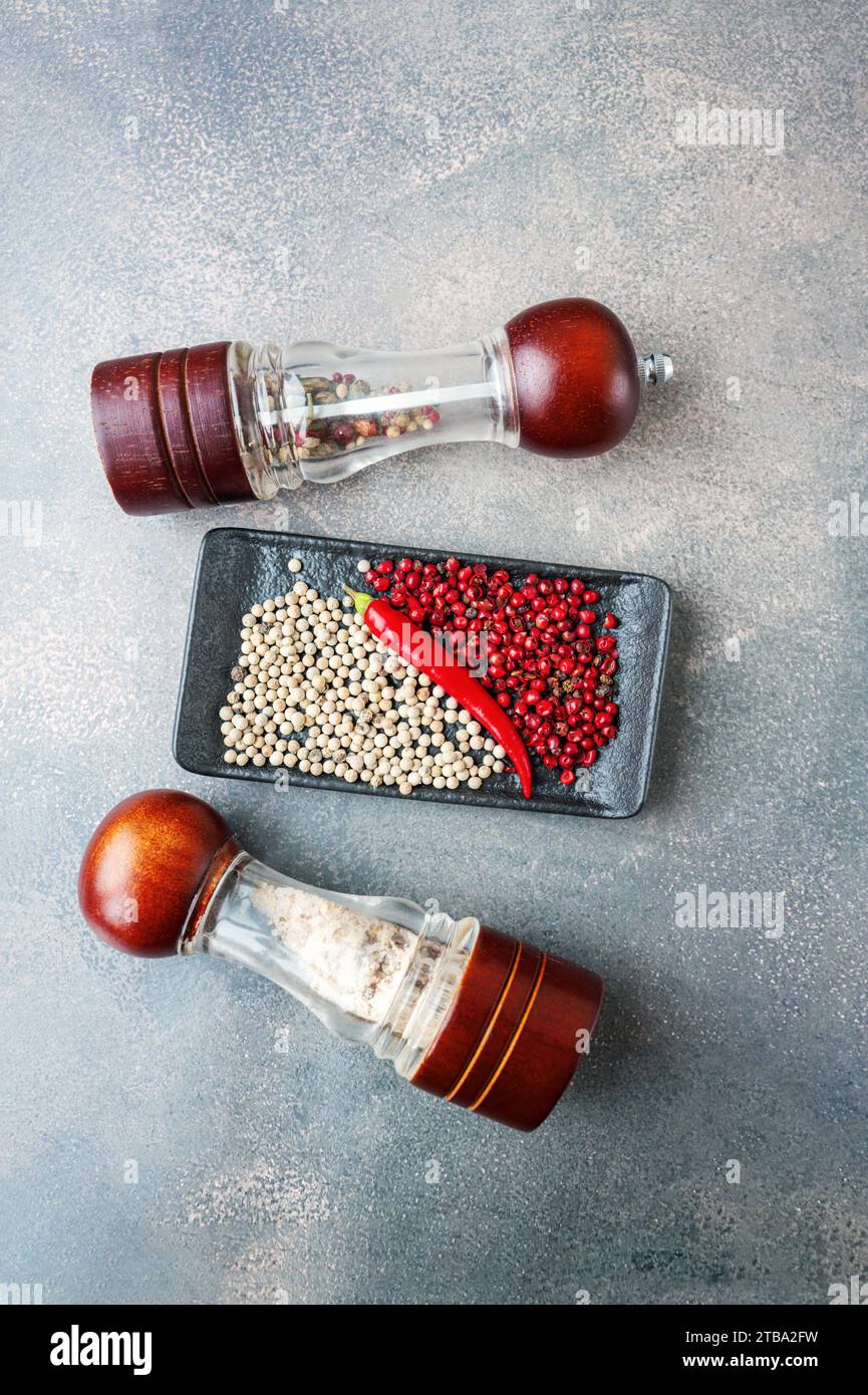 Pepper mills with different types of peppers and sea salt. Spices in glass grinding mills. Top