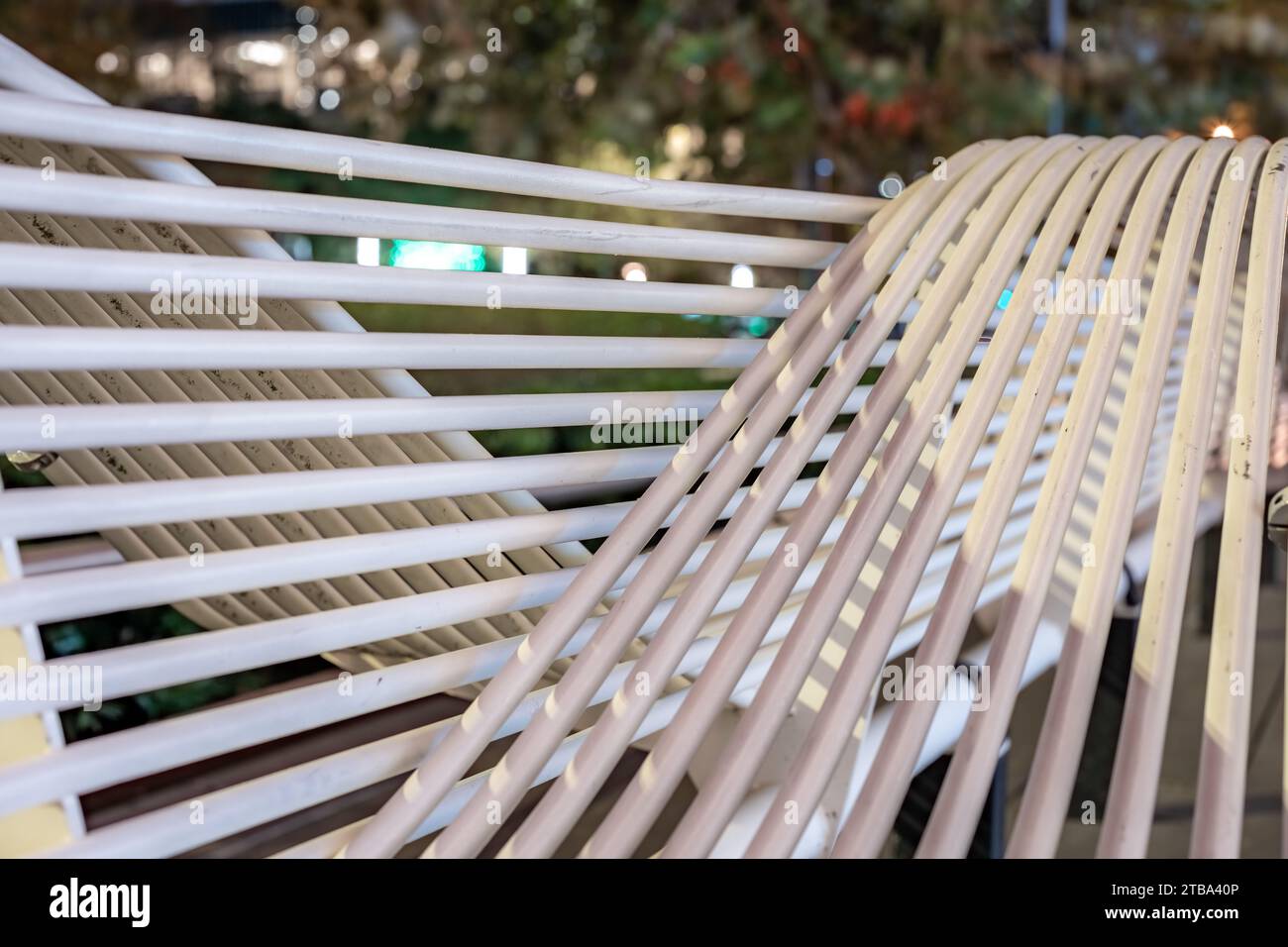 Night time closeup photo of white tube structure park bench in a urban city environment. Stock Photo