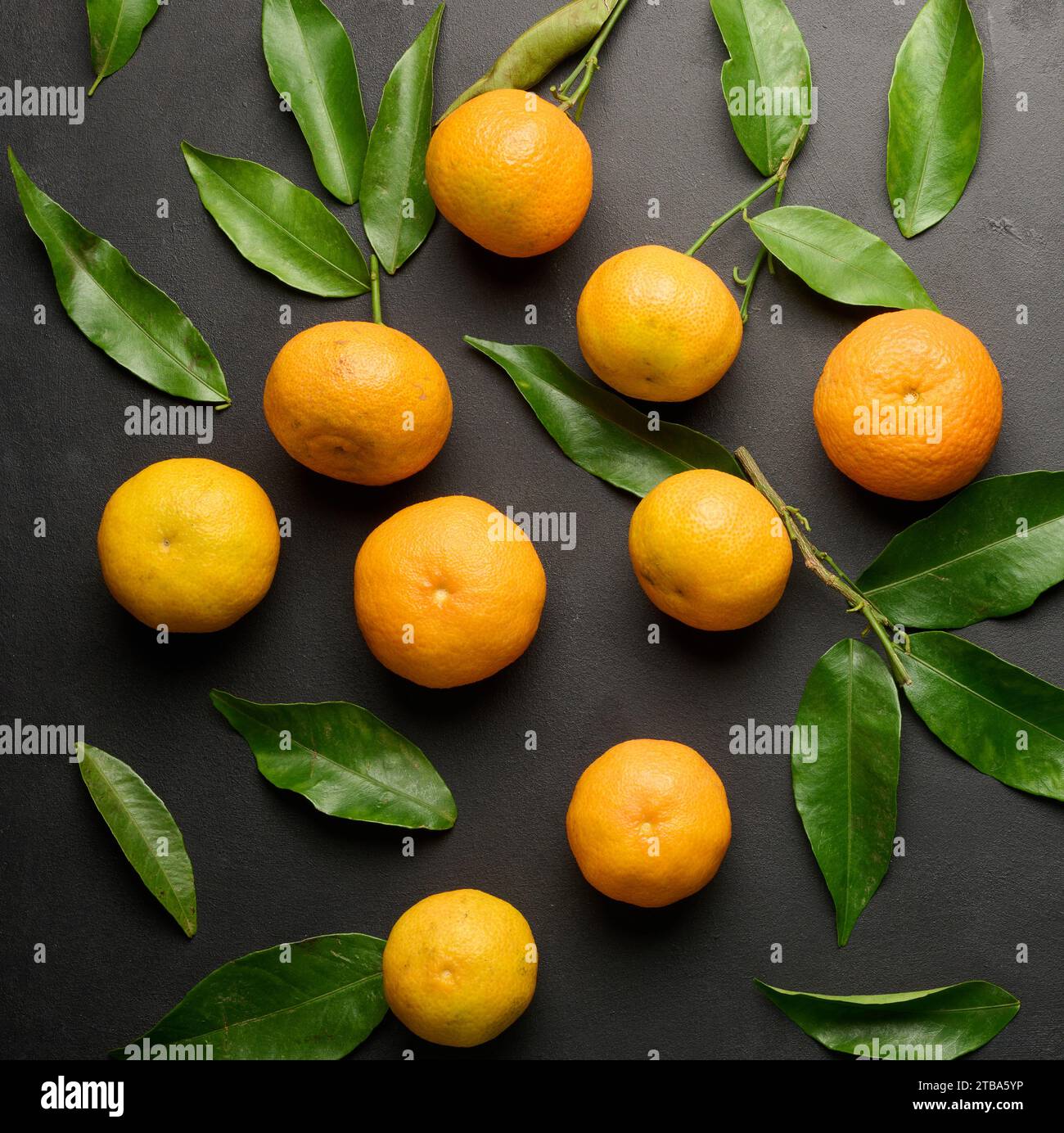 A ripe clementine with green leaves on a black table, top view Stock Photo Alamy