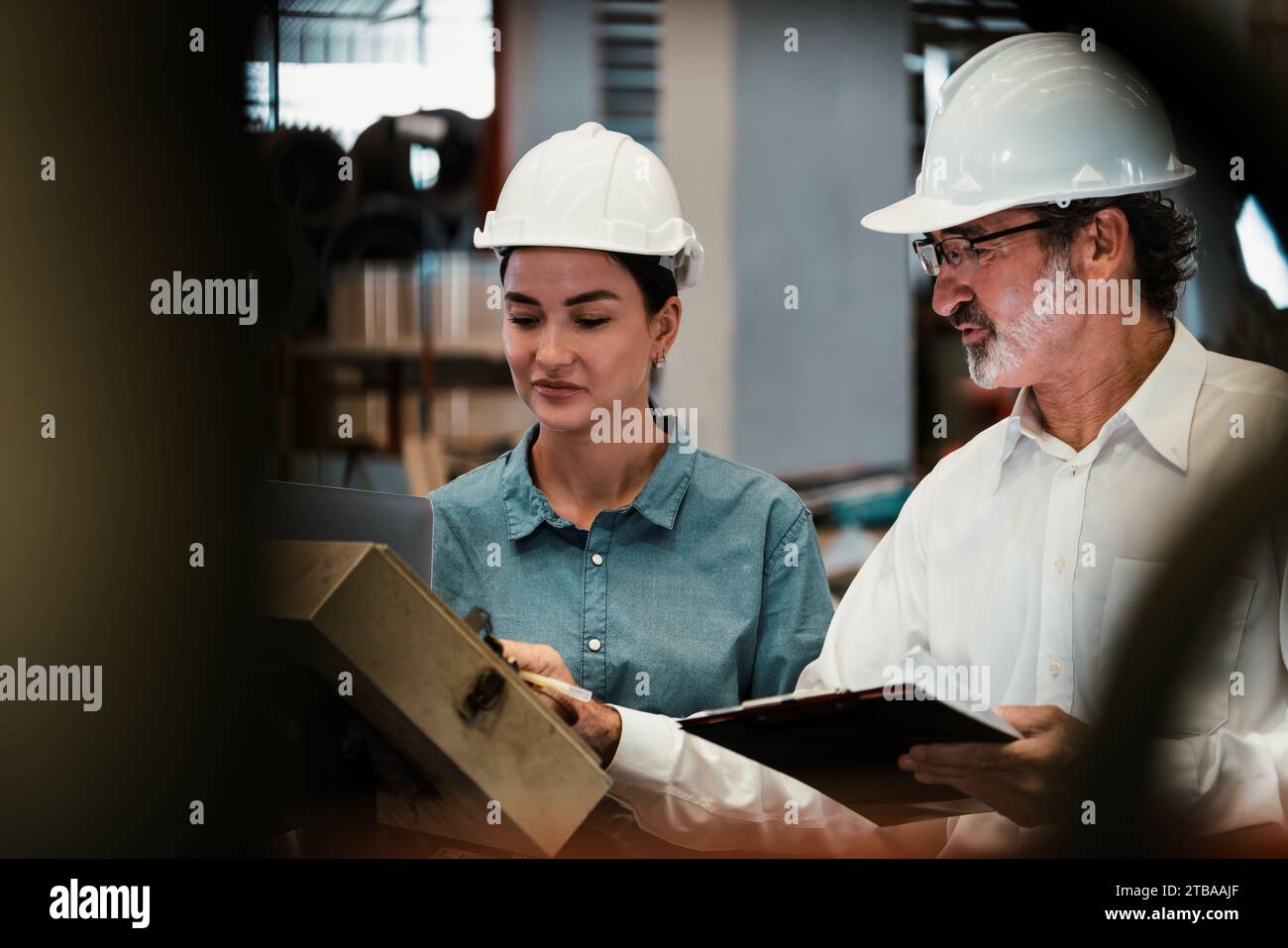 Factory manager inspecting industrial steel machinery and overseeing
