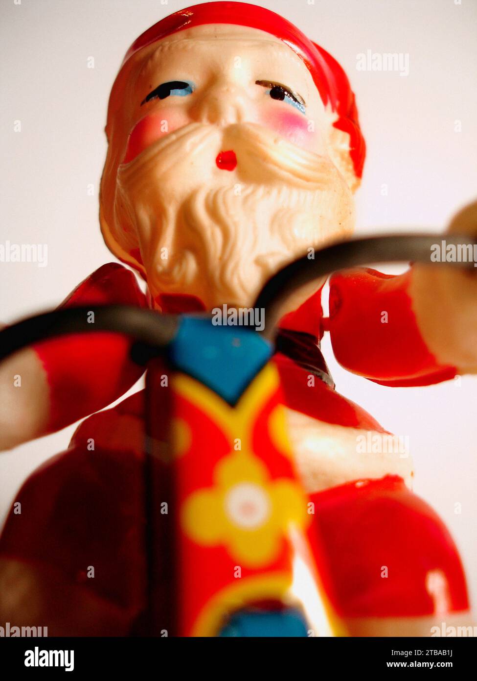 Close up a vintage Father Christmas tin toy. Full traditional Santa costume with trademark white moustache and beard and rosey cheeks sitting on a motorbike. Stock Photo