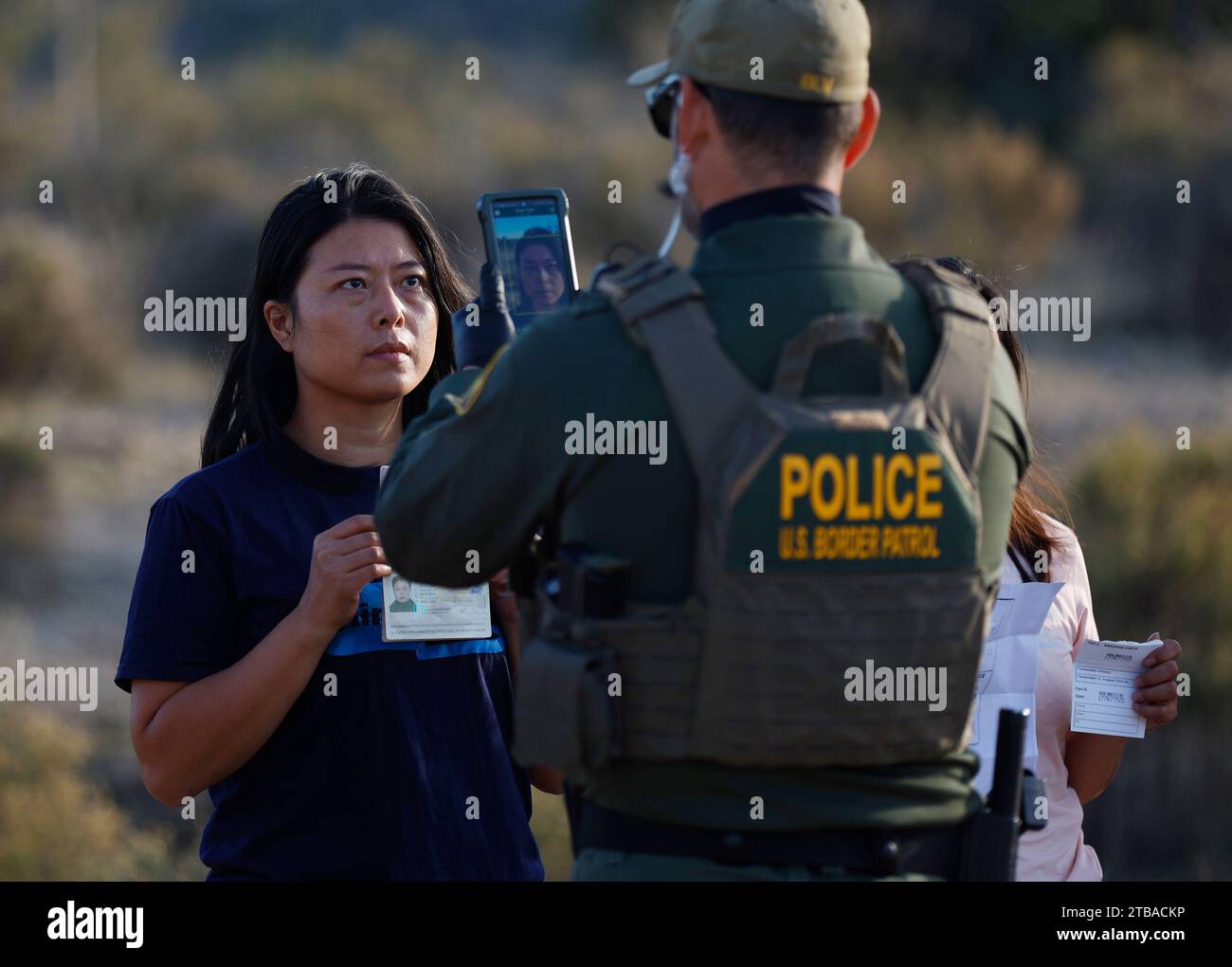 Jacumba Hot Springs, California, USA. 3rd Dec, 2023. A female asylum seeking migrant from China holds up her passport and paperwork as she is photographed by a U.S. Border Patrol agent in an open-air holding area as they prepare to board a bus to a processing facility near to the small, desert San Diego County border community of Jacumba Hot Springs. The U.S. is seeing a big increase in Chinese immigrants arriving using a relatively new and perilous route through Panama's Darien Gap jungle, thanks in part to social media posts and videos providing step-by-step guidance. (Credit Image: © K.C Stock Photo