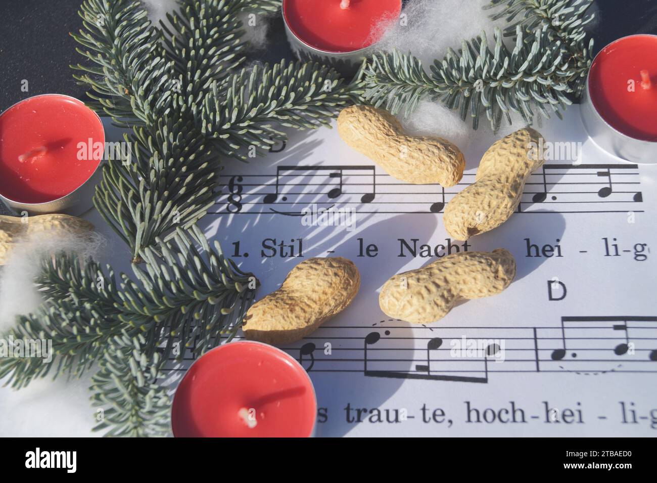 sheet of music with the Christmas song 'Stille Nacht, Heilige Nacht', decorated with tea lights, peanuts and fir twigs Stock Photo