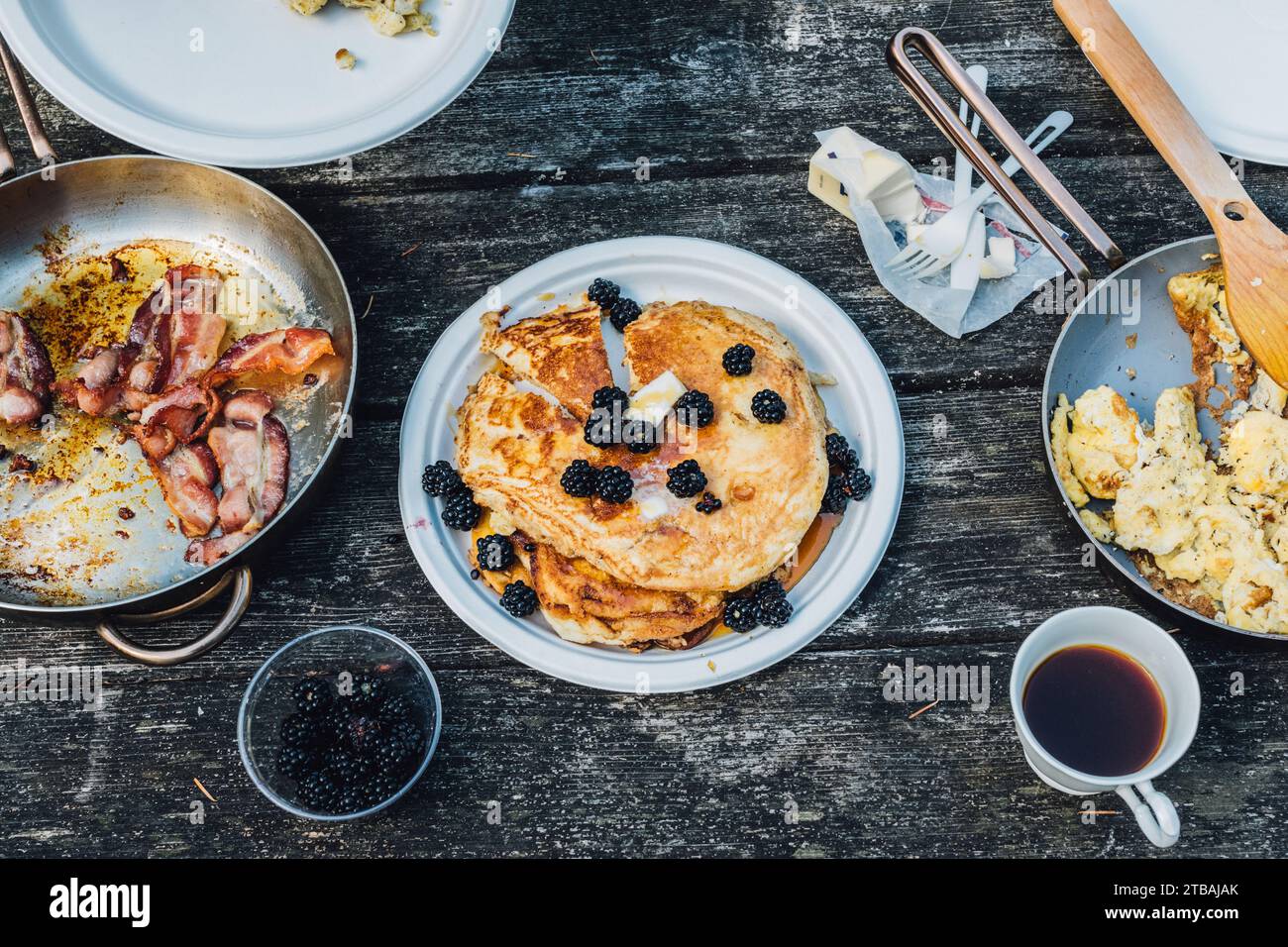 high angle view of American breakfast camping tabletop with pancakes, bacon, scrambled eggs, coffee Stock Photo