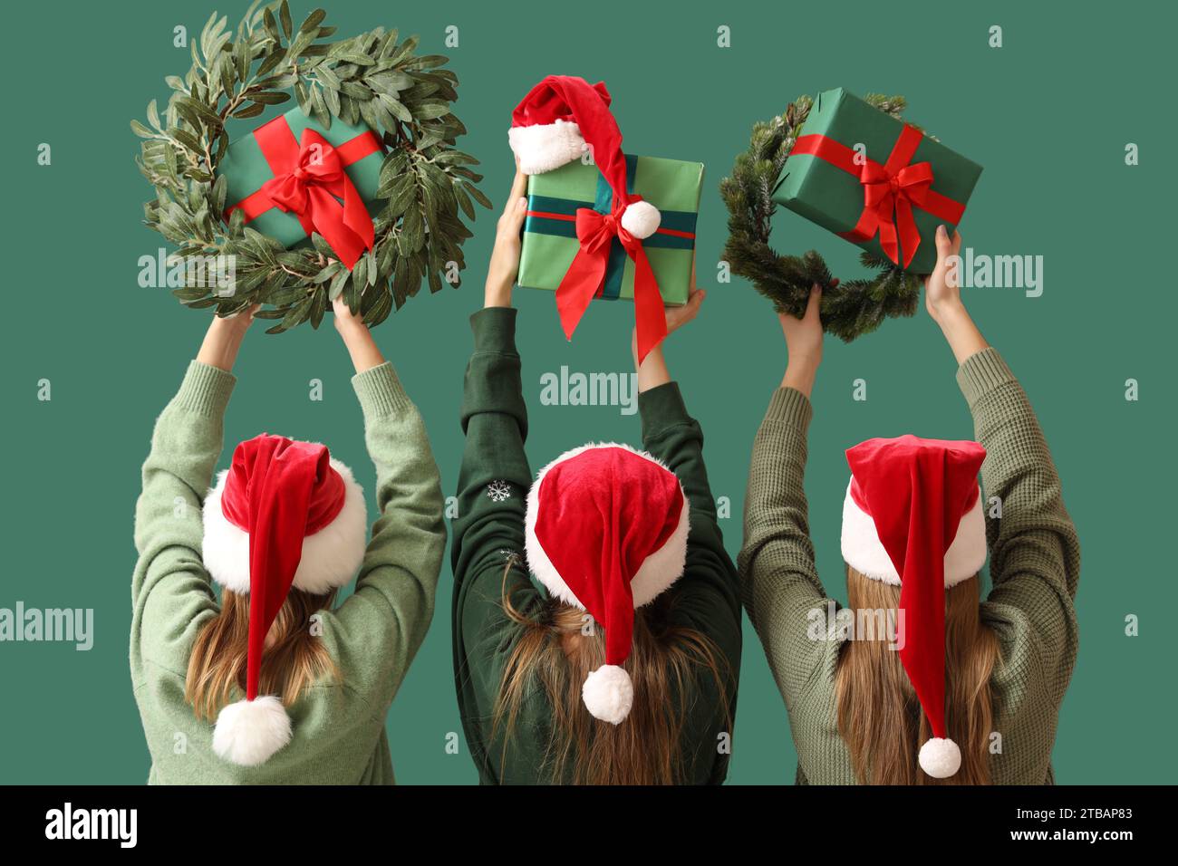 Women in Santa hats holding Christmas gift boxes and wreathes on green ...