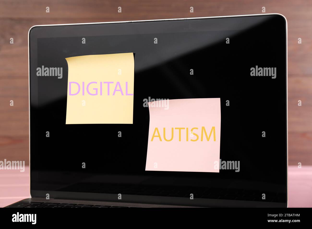 Sticky notes with phrase Digital Autism attached to laptop on table, closeup. Addictive behavior Stock Photo