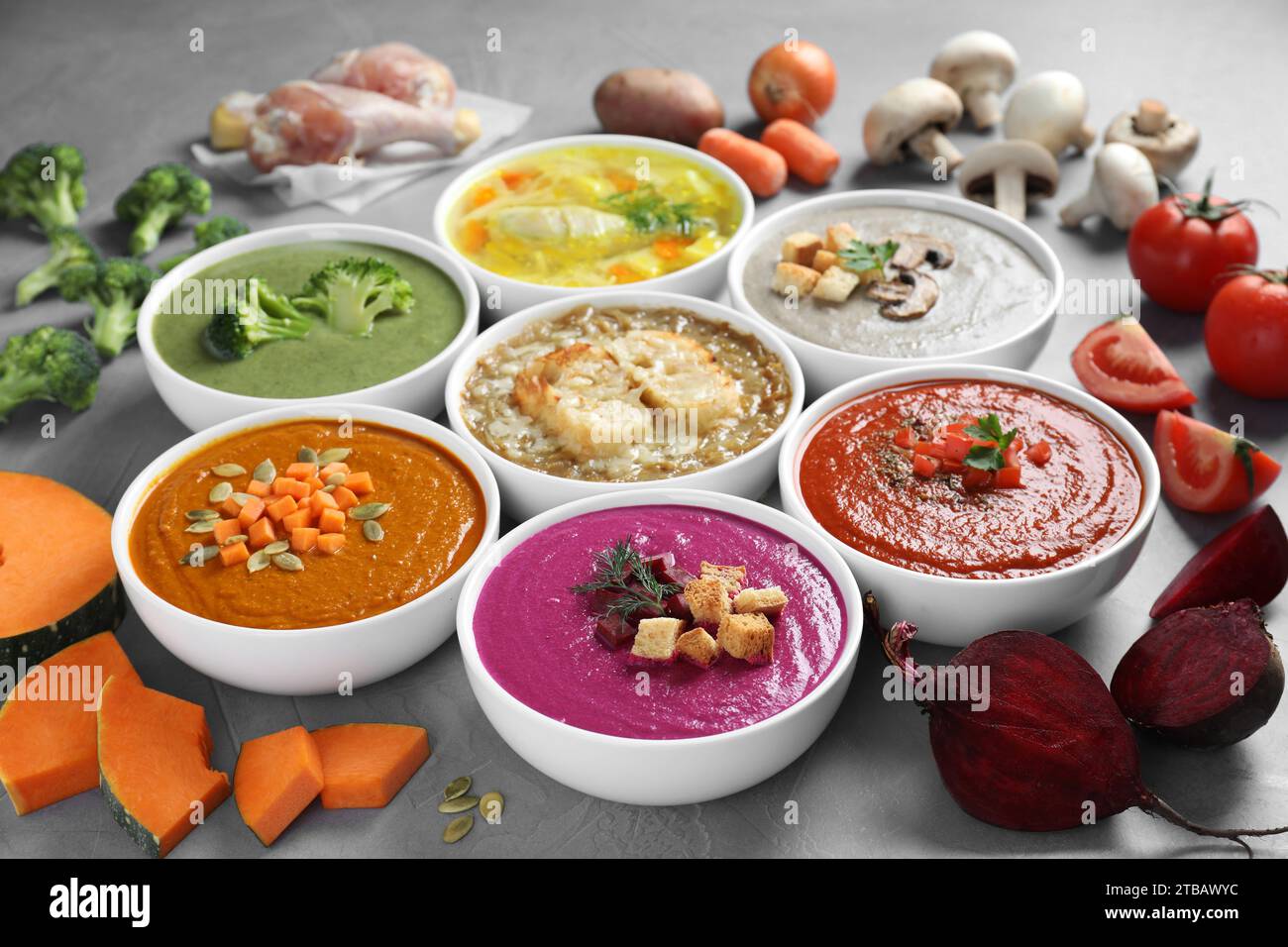 Tasty broth, different cream soups in bowls and ingredients on table