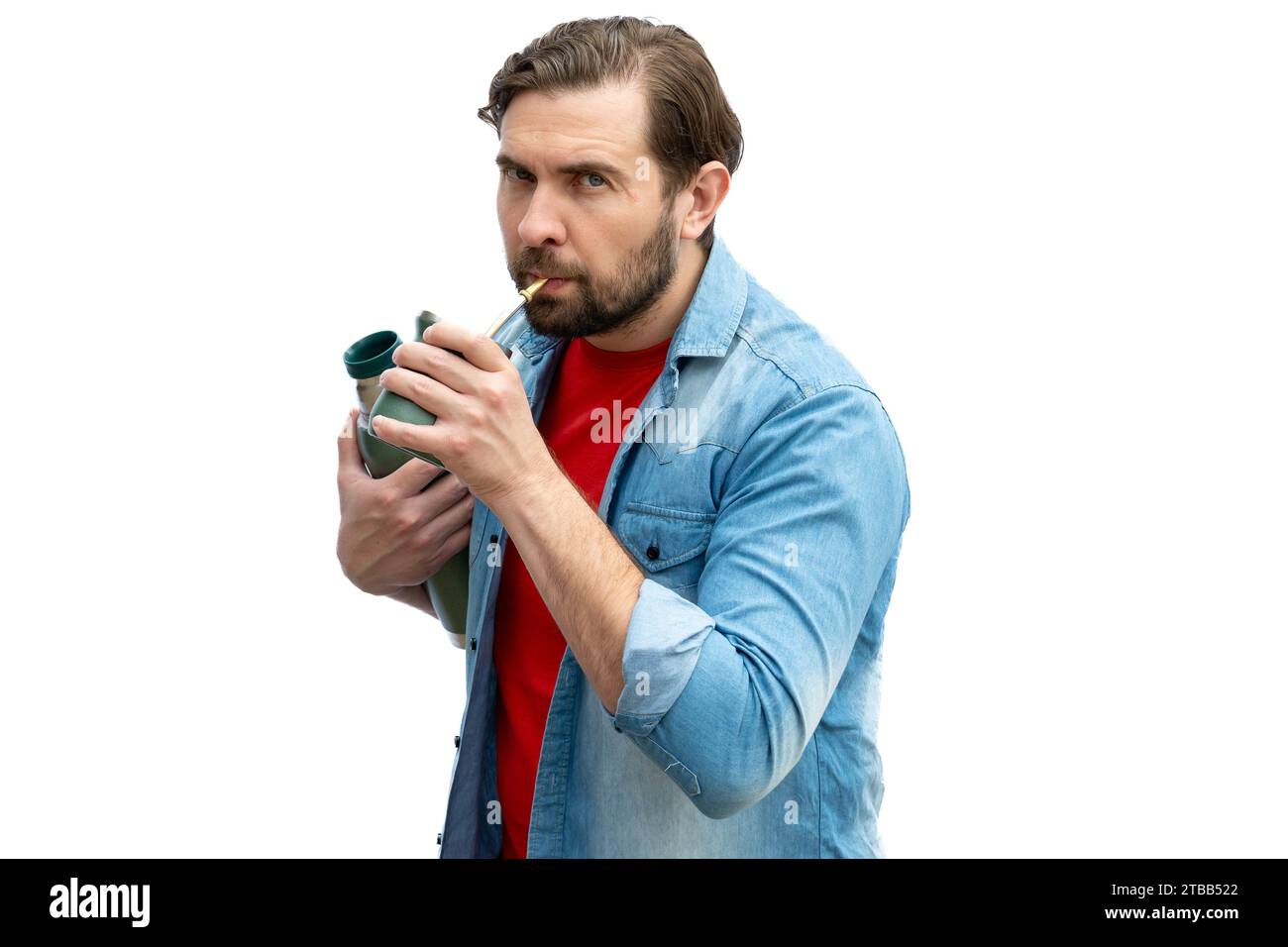 Young man drinking mate, holding the thermos in one arm. Stock Photo