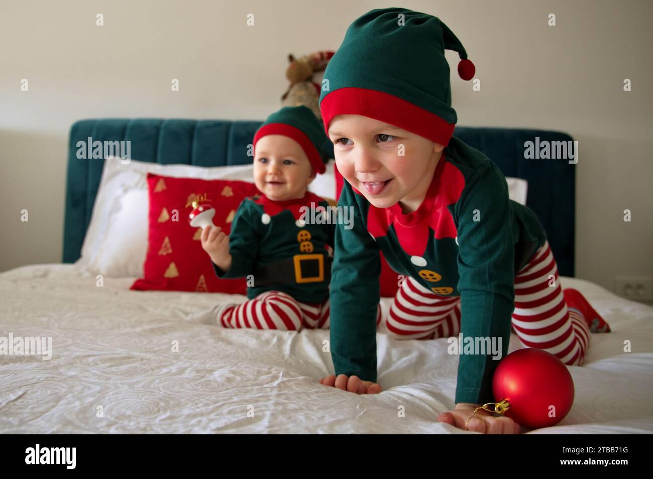 Baby girl and toddler dressed as elves having fun on a bed Stock Photo