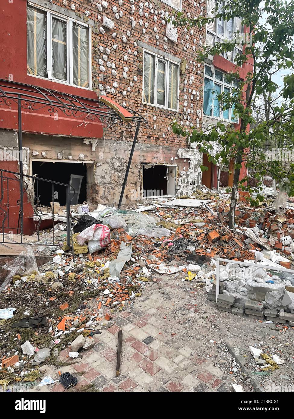 Irpen, Ukraine. May 07. 2022 Mountains of construction debris on the sidewalk under the house where the projectile hit, broken bricks and windows Stock Photo