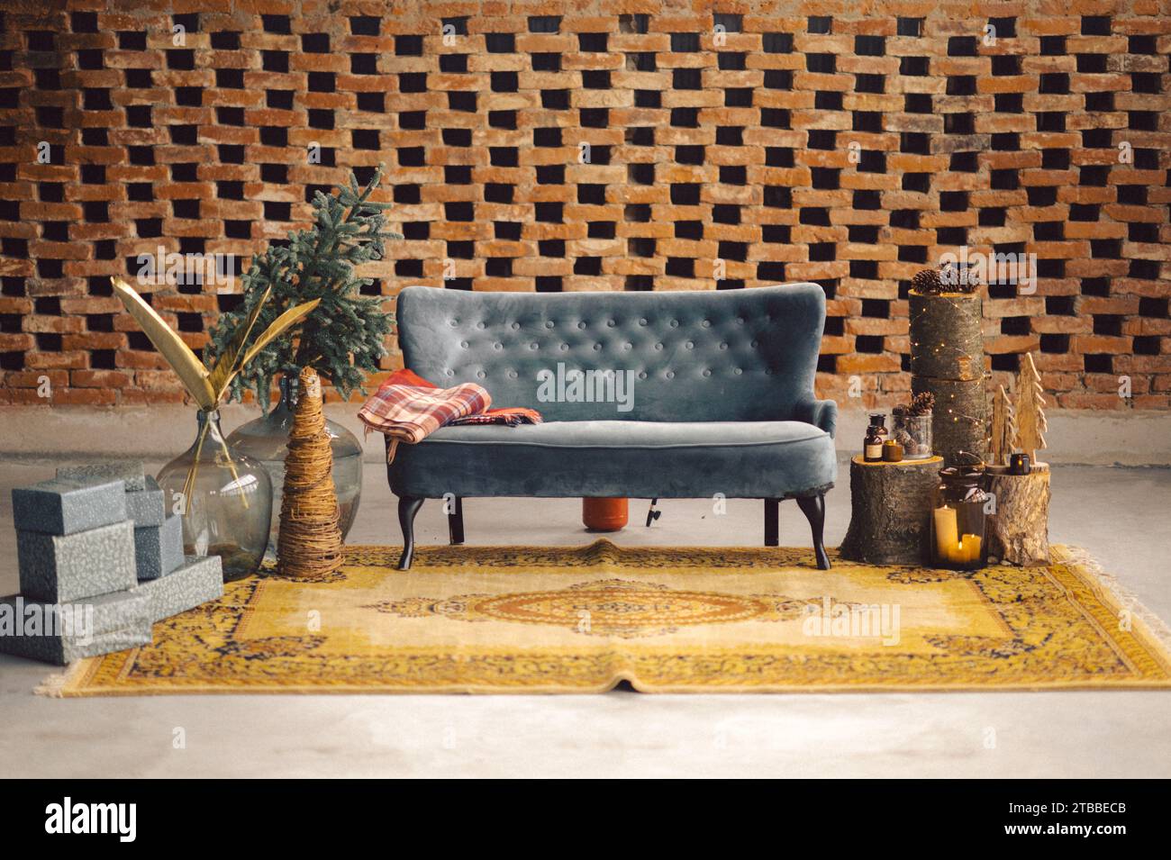A velvet sofa in a festive setting against a brick wall background, ideal for Christmas celebrations Stock Photo