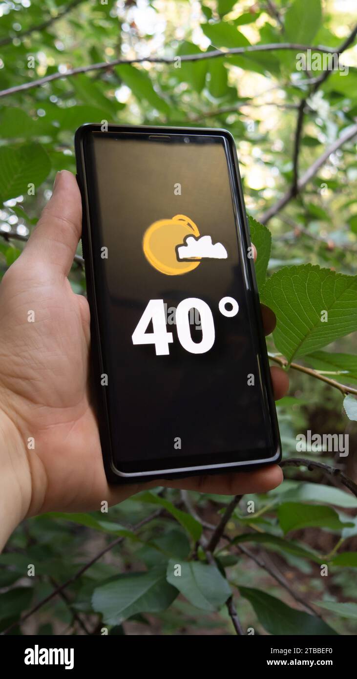 Smartphone thermometer displaying 40 degrees Celsius, indicating warm temperature during a hot summer heatwave weather in Europe, Earth. Stock Photo