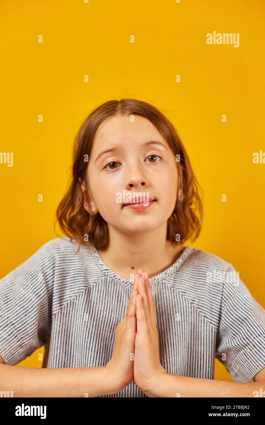 Pleading teen girl on yellow studio background Stock Photo - Alamy