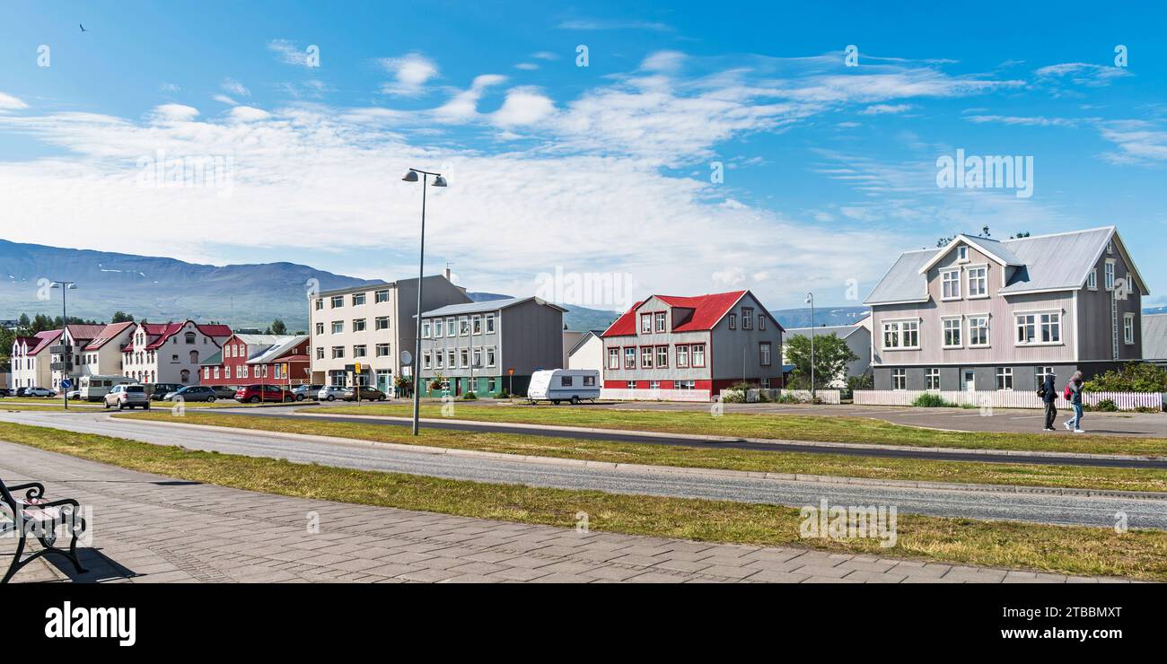 wide walkway on a pleasant street lined with small apartment buildings in Akureyri Iceland under a partly cloudy summer sky Stock Photo