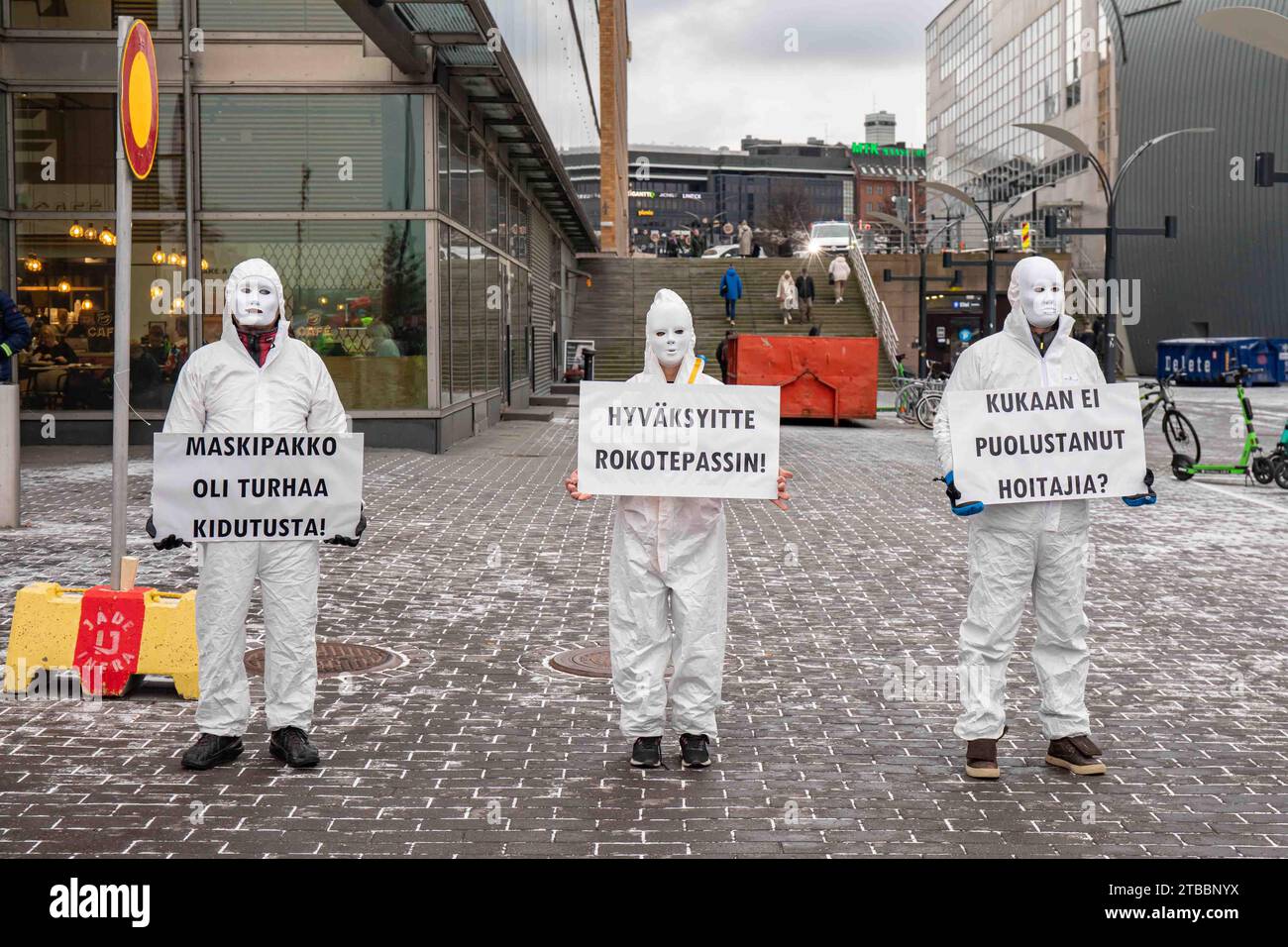 Masked Corona deniers in white overalls or boiler suites demonstrating and holding placards by Kansalaistori in Helsinki, Finland Stock Photo