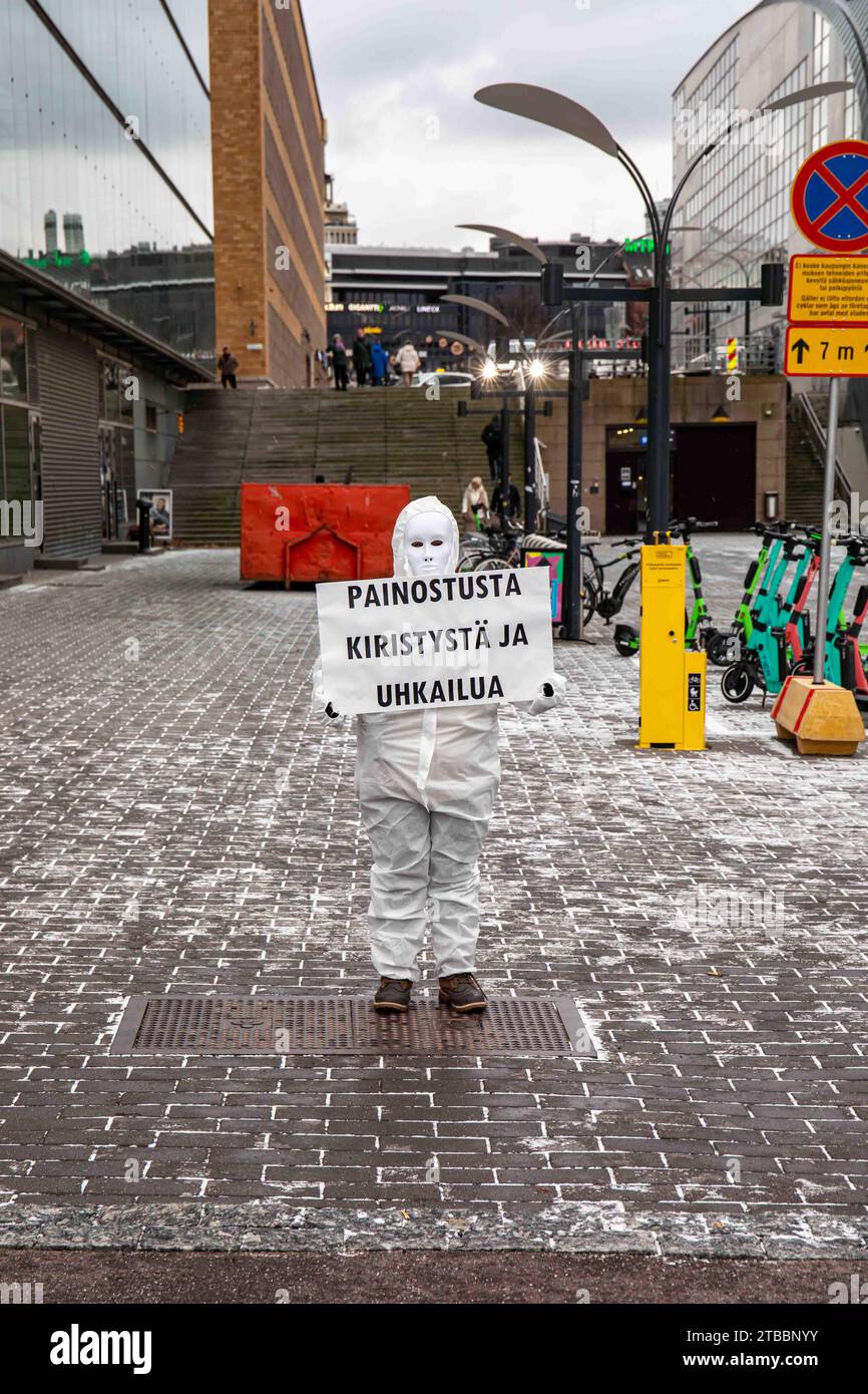 Painostusta kiristystä ja uhkailua. Masked COVID-19 denier in white boiler suit holding a sign in Helsinki, Finland. Stock Photo