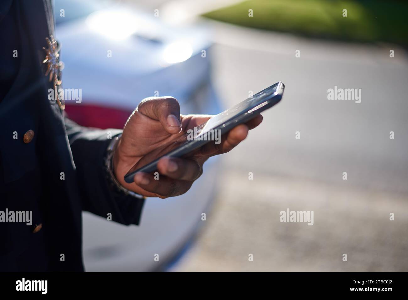 Cropped image of Black business man holding cellphone while outside Stock Photo