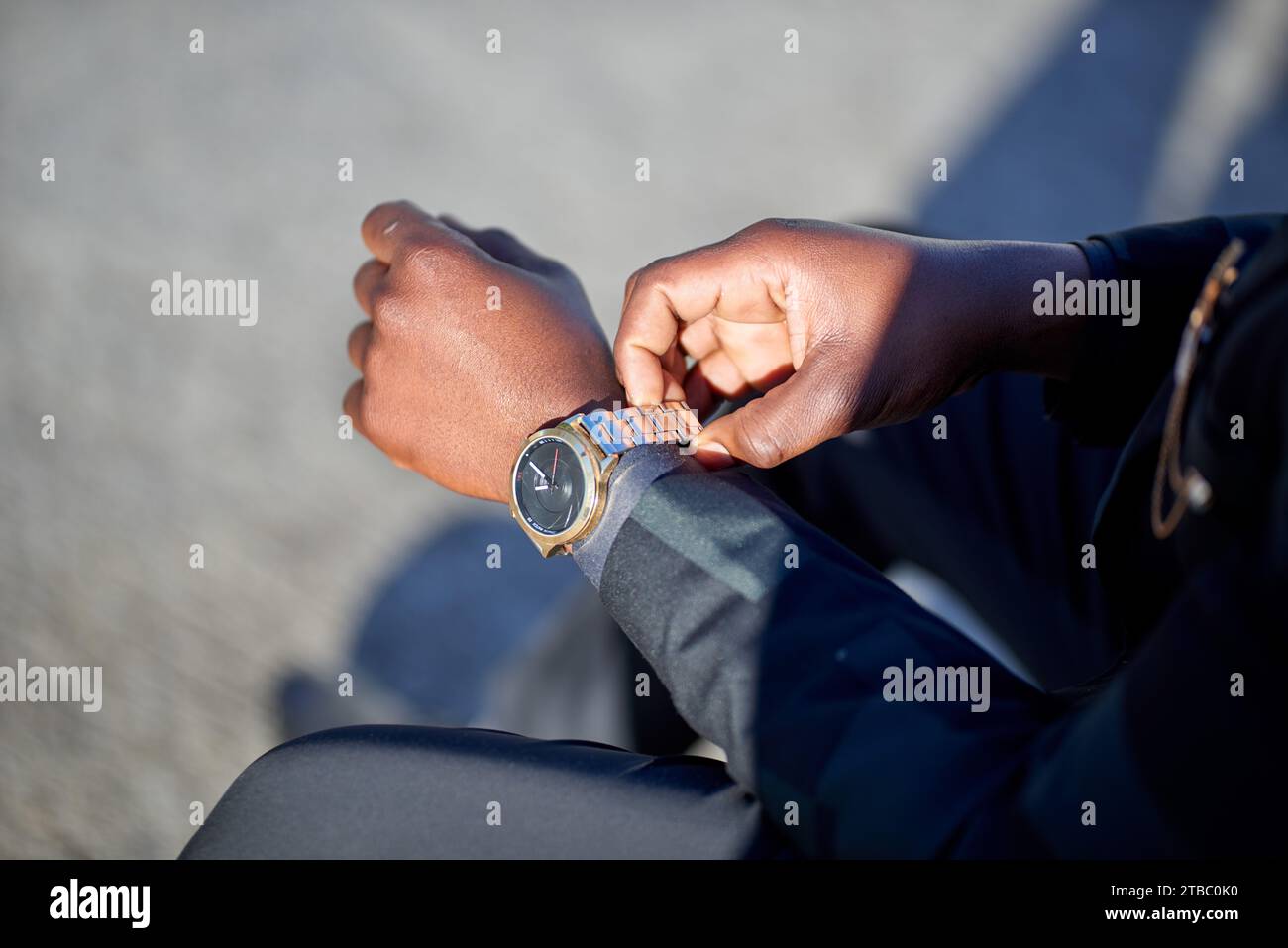 Cropped image of Black man in formal wear putting on his watch Stock Photo