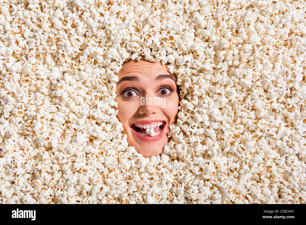 Above view photo of cheerful astonished overjoyed girl face buried isolated on background with full popcorn Stock Photo