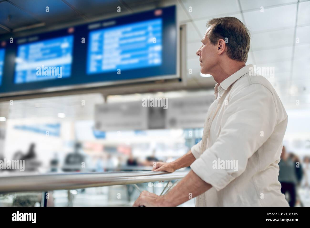 Side view of traveler man posing with timetable on railway station. Stock Photo