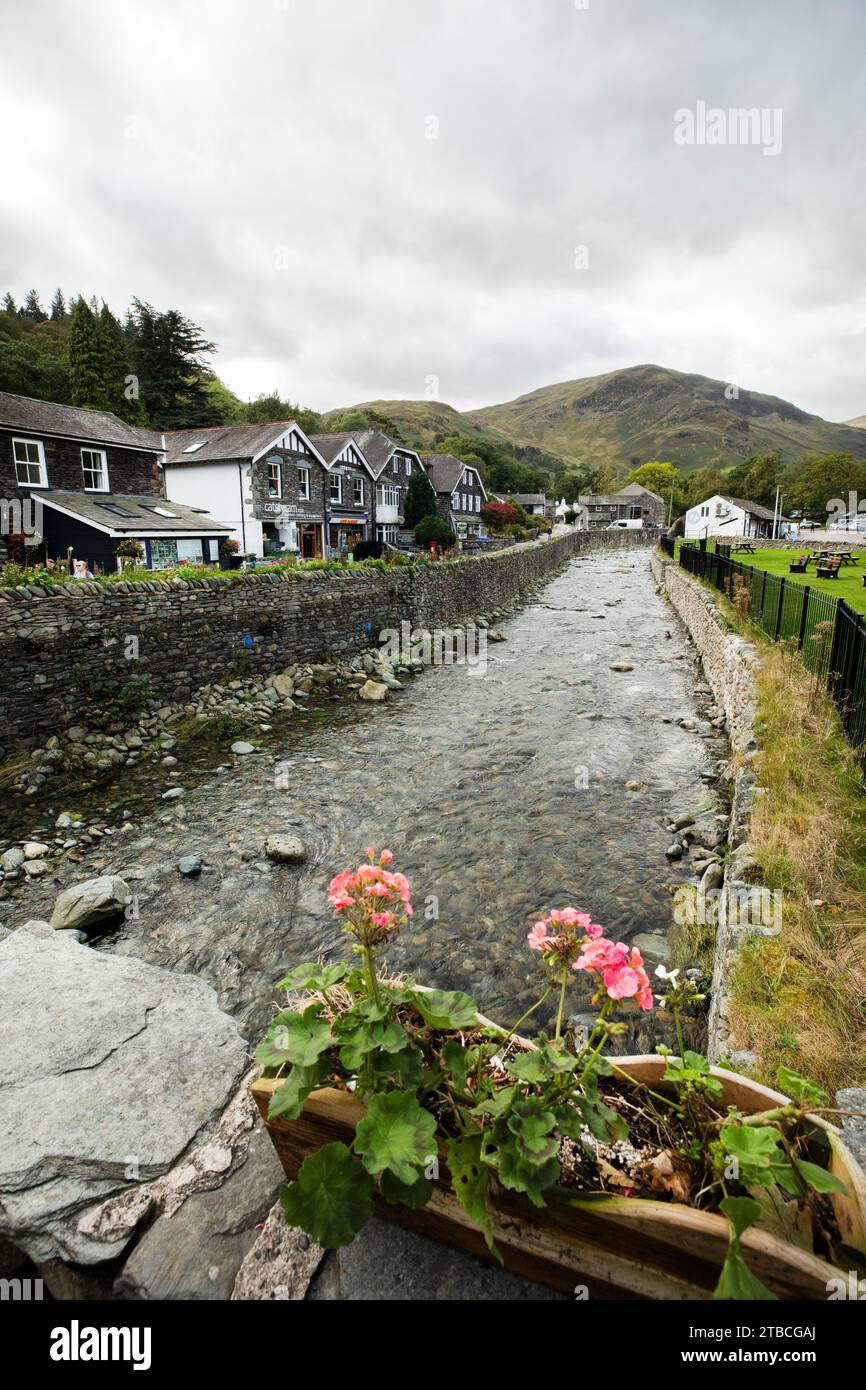 Glenridding Beck running between stone walls with houses on one side and picnic area on the other bank at glenridding village, Lake District, Cumbria Stock Photo