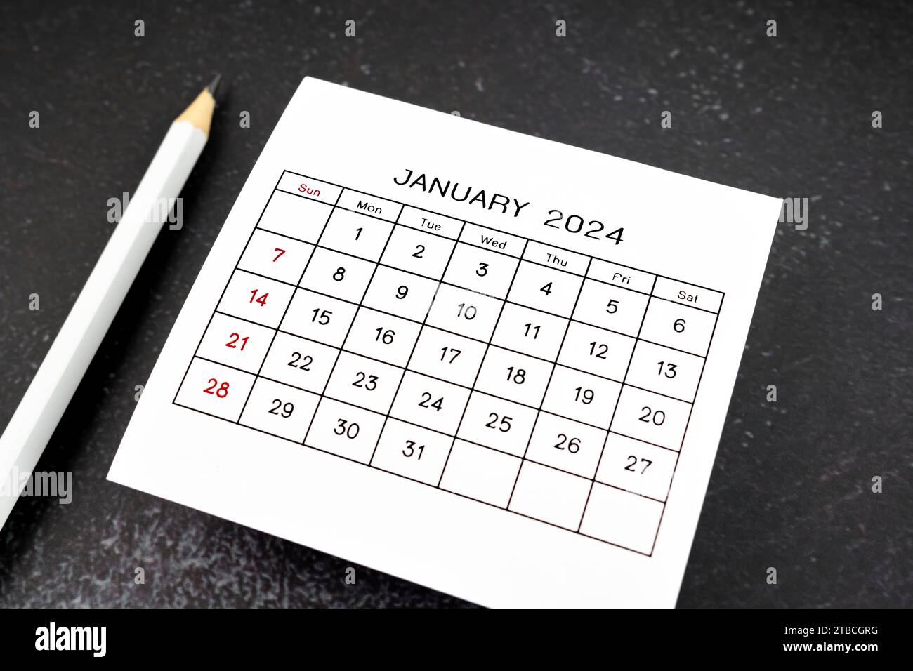 White calendar page for January 2024 and pencil on black background ...