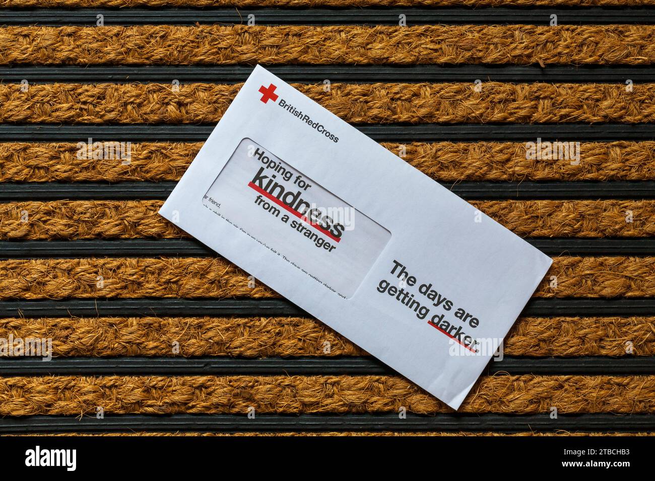 Post on door mat - charity appeal, Christmas appeal from British Red Cross hoping for kindness from a stranger the days are getting darker Stock Photo