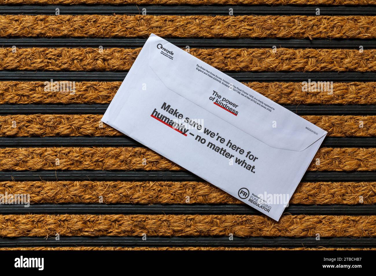 Post on door mat - charity appeal, Christmas appeal from British Red Cross back of envelope the power of kindness Stock Photo