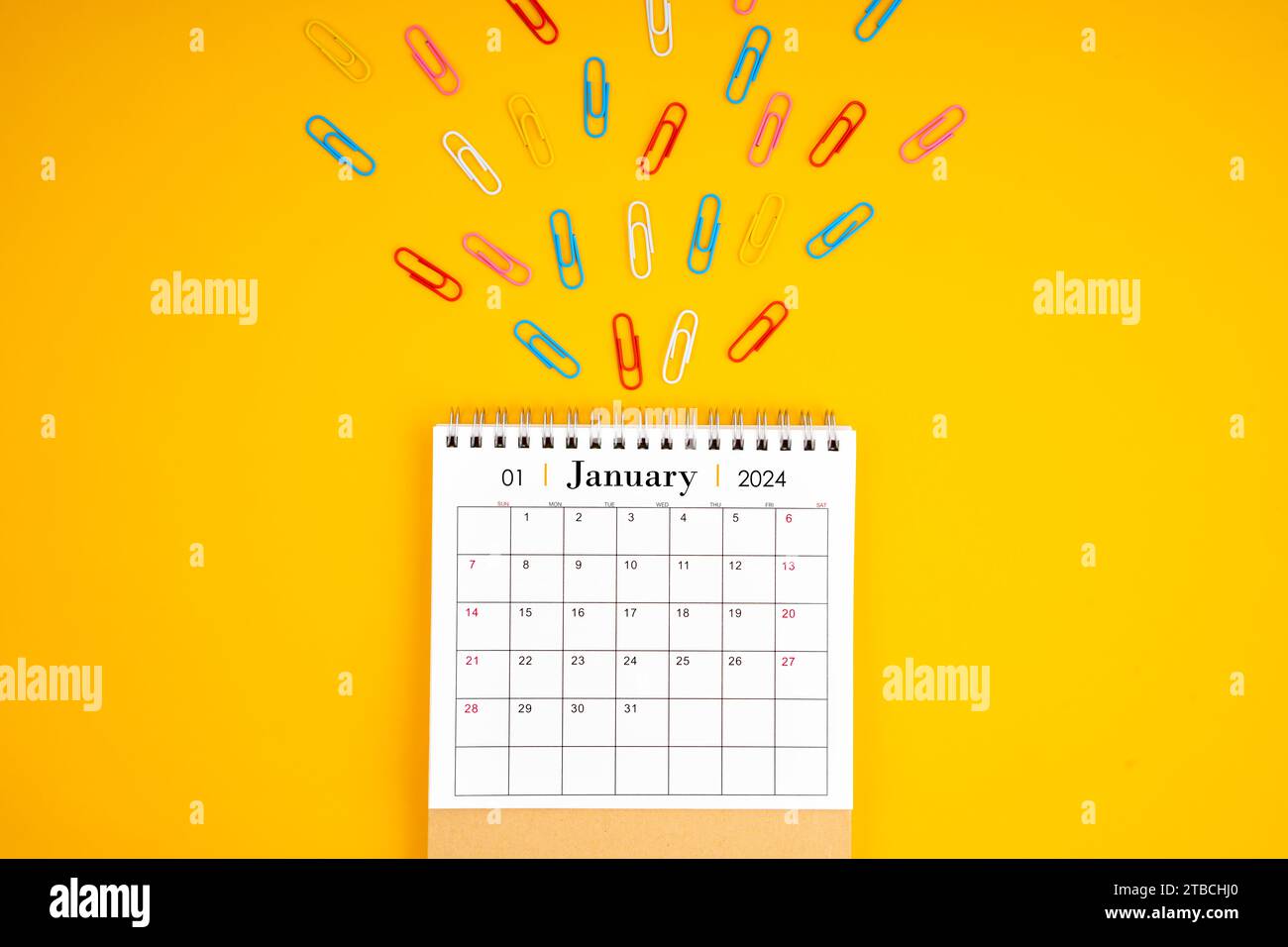January 2024 desk calendar and colorful metal paperclips on yellow ...