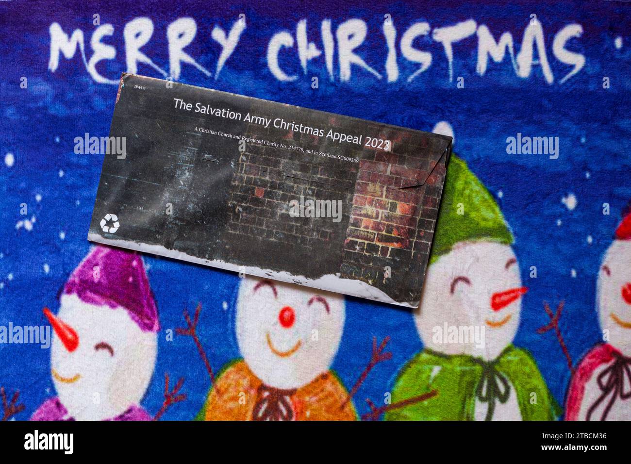 Post mail on Merry Christmas doormat - Christmas appeal from the Salvation Army back of envelope Stock Photo