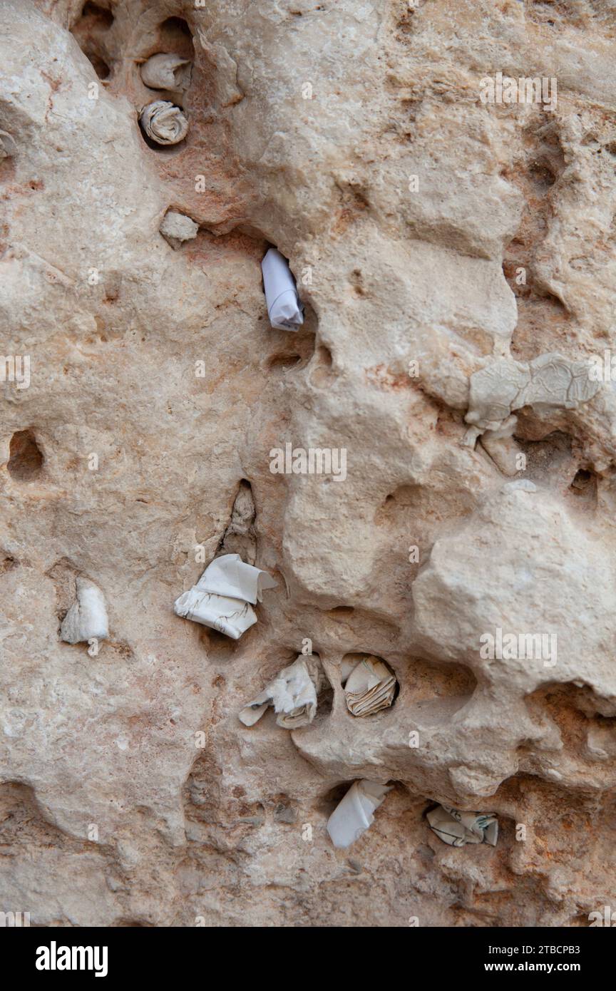 Tiny, folded pieces of paper with written notes addressed to God are crammed into cracks