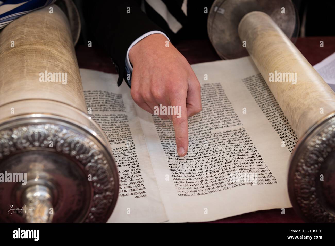 A man reading from the Torah  uses his finger as a pointer or yad to guide him through the Hebrew text. Stock Photo