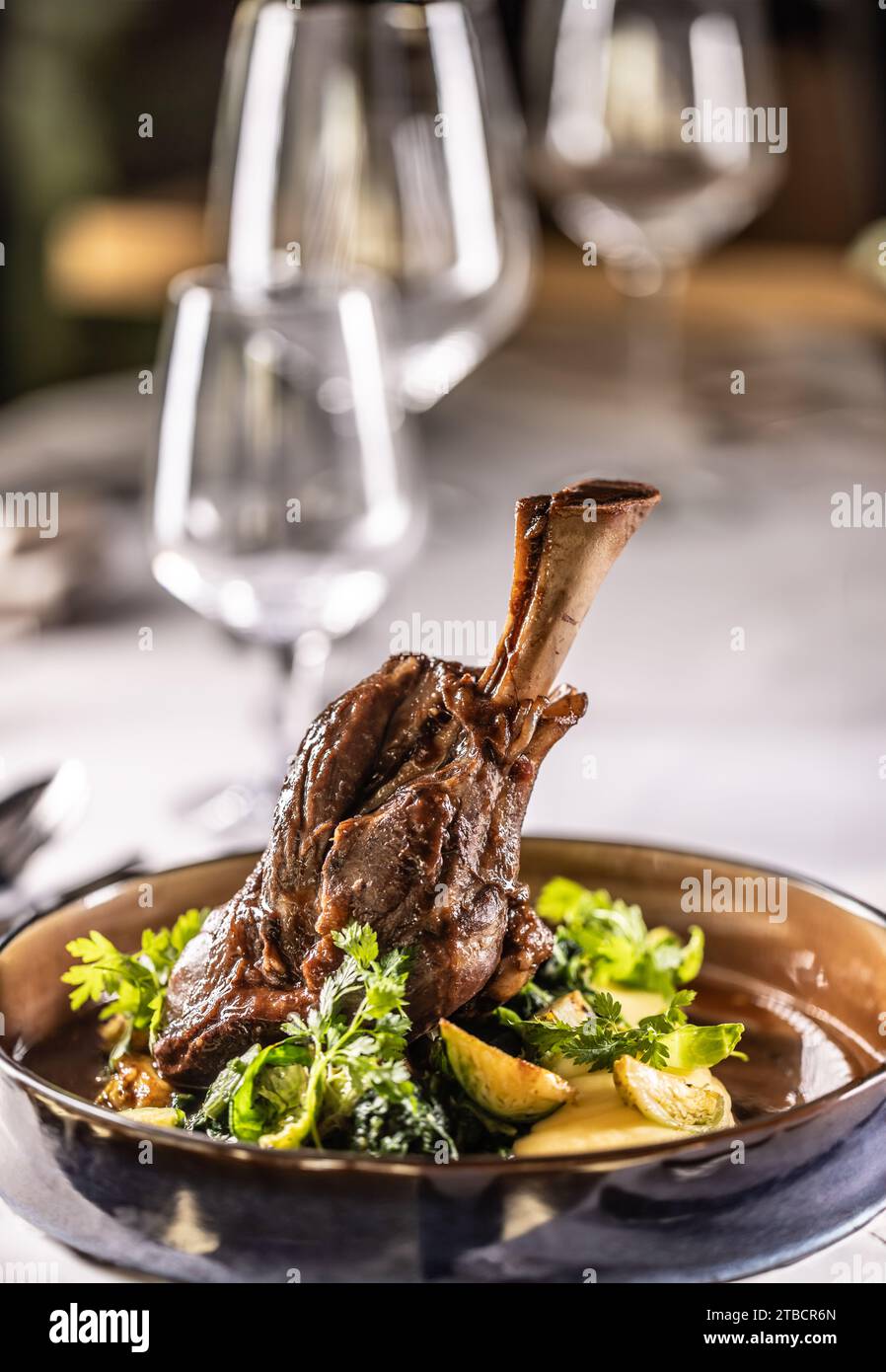 Confit leg of lamb on mashed potatoes with creamy kale, demi glace sauce and herbs in the hotel restaurant. Stock Photo