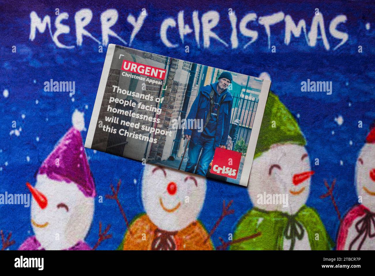 Post on Christmas mat, Merry Christmas - charity appeal from Crisis - thousands of people facing homelessness will need support this Christmas Stock Photo