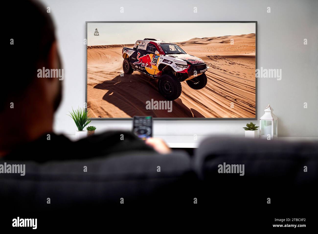 Man watching Dakar rally race on smart TV. Sports Live transmission concept. ROSARIO, ARGENTINA - DECEMBER 2, 2023. Stock Photo