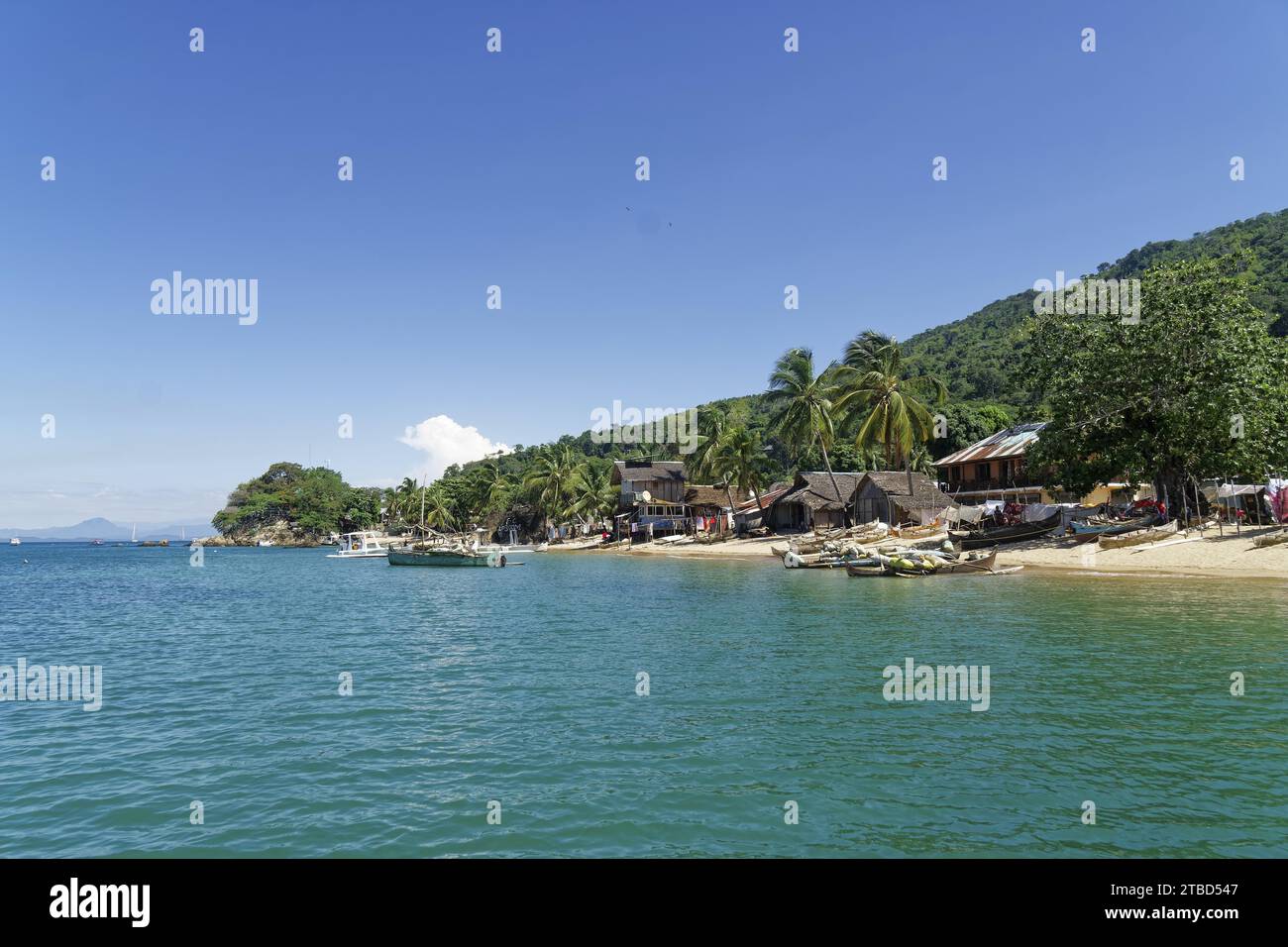 Beach, dugout boats, fishing village, huts, palm trees, dark turquoise-green water, Ampangorinana, Nosy Komba, Madagascar Stock Photo