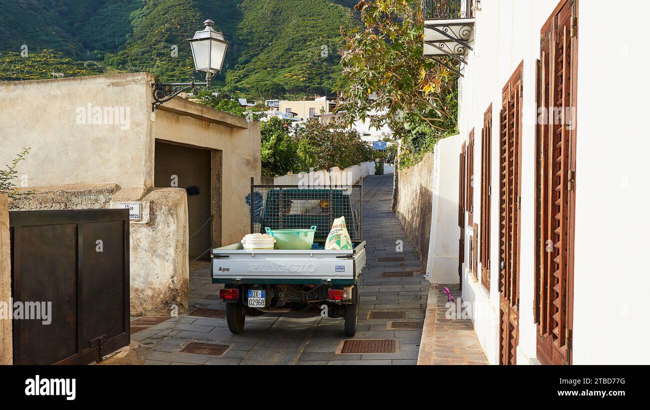 Ape, tricycle, riding down an alley, lantern, house wall, Malfa, Salina, Aeolian Islands, Sicily, Italy Stock Photo